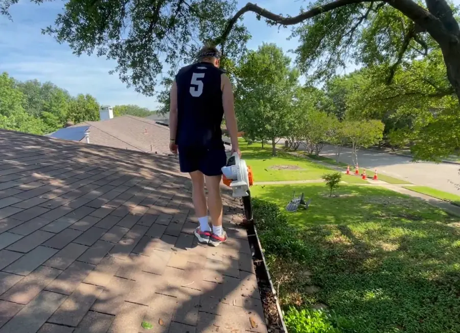 Crew member scooping composted leaf matter from a gutter — gutter cleaning company Jacksonville FL