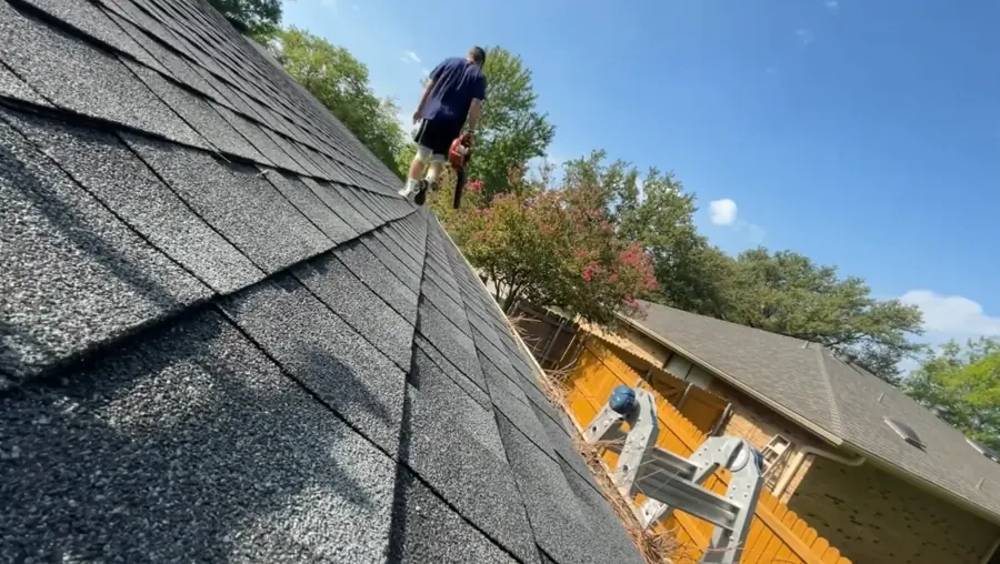 Red work gloves scooping wet debris from an aluminum gutter during gutter cleaning in Jacksonville FL