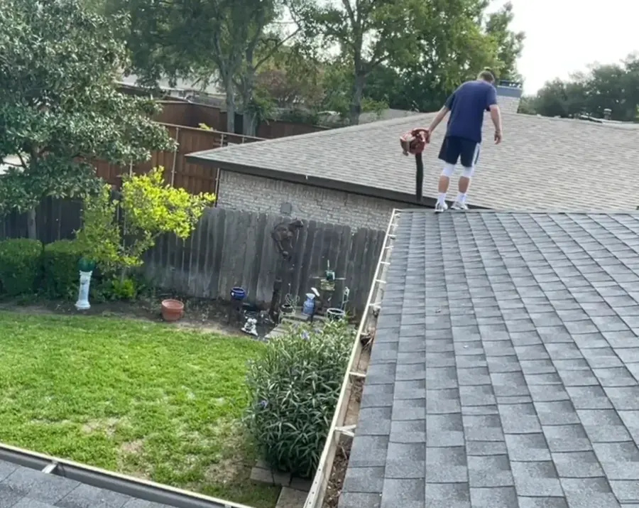 Technician on a rooftop clearing gutters with a blower during gutter cleaning in Jacksonville FL